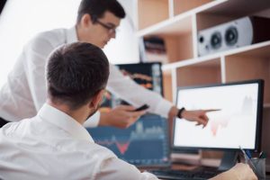 Two network engineers discussing Kamailio server performance on a monitor