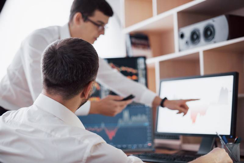 Two network engineers discussing Kamailio server performance on a monitor