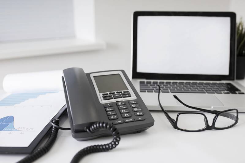 A desk with a VoIP phone and a laptop running the CX phone system