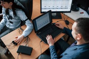 Two IT professionals reviewing SLA compliance reports on a laptop